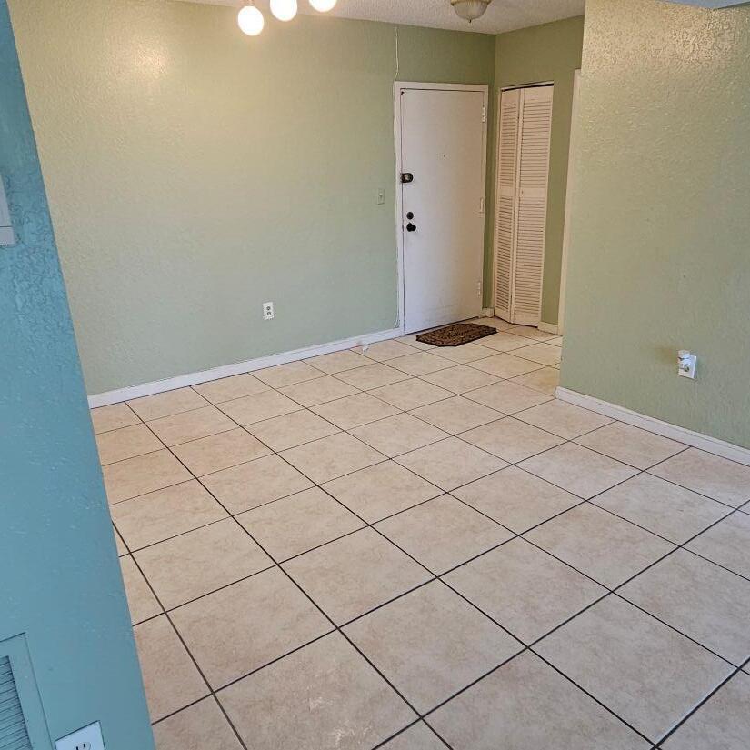 An empty room with light green walls, tiled flooring, a white door, and a closet — 4174 Inverrary Drive # 603, Lauderhill FL 33319, LAUDERHILL, FL