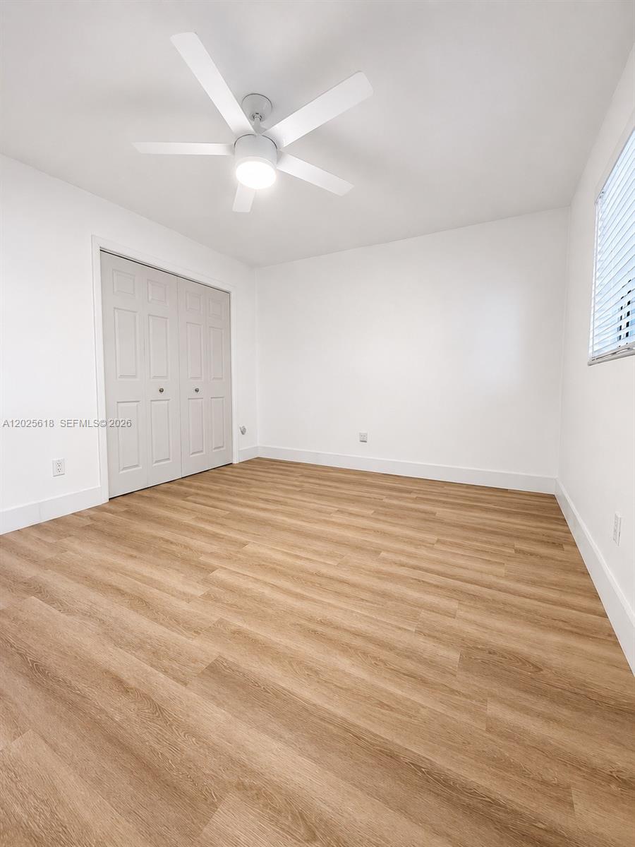This bedroom features white walls, light wood-look flooring, a ceiling fan, and closet doors — 421 NE 1st St # 221, Hallandale Beach FL 33009, HALLANDALE BEACH, FL