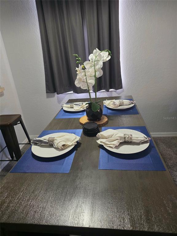 A dining table is set with four place settings and a central orchid centerpiece — 746 TERRA LAGO STREET, DAVENPORT, FL