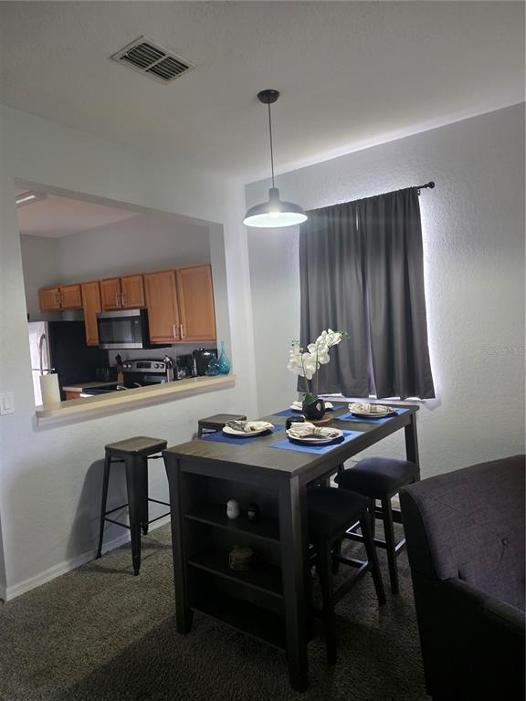 A dining area with a dark wood table and stools sits adjacent to a kitchen pass-through — 746 TERRA LAGO STREET, DAVENPORT, FL