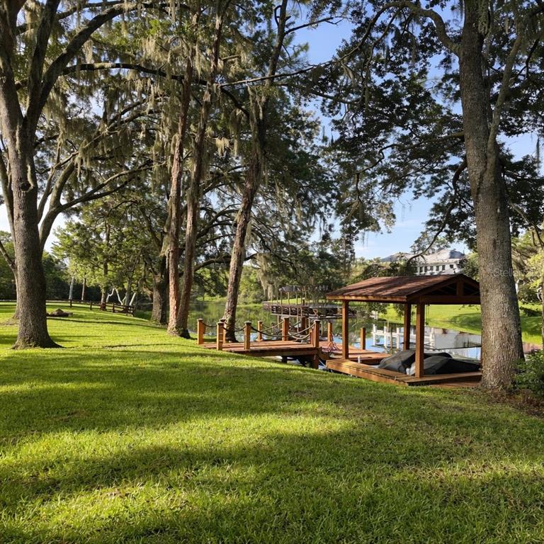 A grassy lawn slopes down to a wooden boat dock on a calm lake — 11102 SHADY OAK STREET, ORLANDO, FL