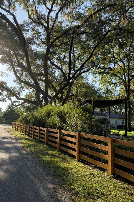 A wooden fence runs along a gravel path beneath large trees with hanging moss — 11102 SHADY OAK STREET, ORLANDO, FL