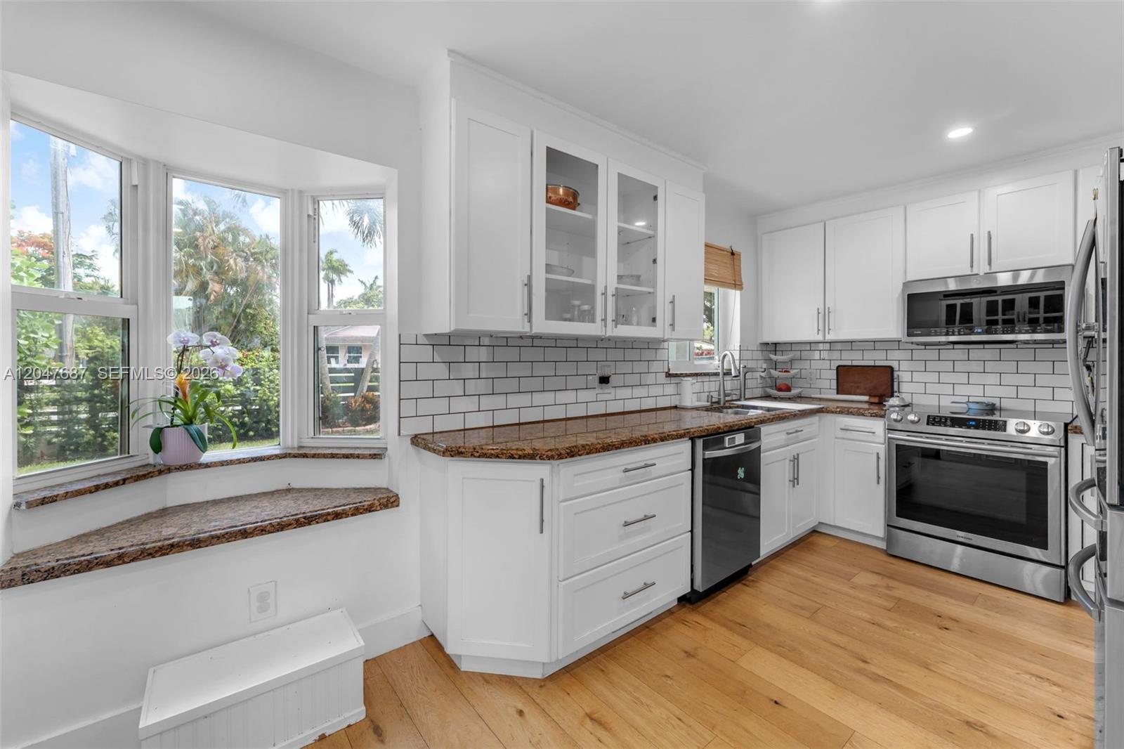 A kitchen features white cabinets, granite countertops, a subway tile backsplash, and a bay window — 4035 SW 14th St, Miami FL 33134, MIAMI, FL