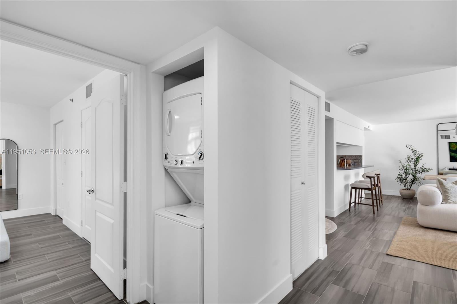A white stacked washer and dryer unit sits in a hallway next to a kitchen — 2647 NW 25th Ave # 507, Miami FL 33142, MIAMI, FL