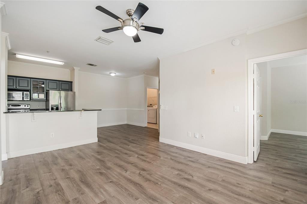 An open-concept living area features wood-look flooring, a ceiling fan, and a kitchen with cabinets — 3611 CONROY ROAD UNIT 835, ORLANDO, FL
