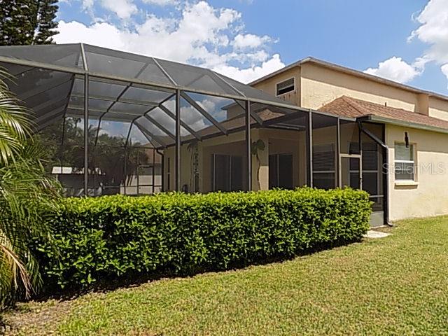 A house exterior features a screened-in pool enclosure and a manicured hedge in the yard — 12507 ROCKROSE GLEN, LAKEWOOD RANCH, FL