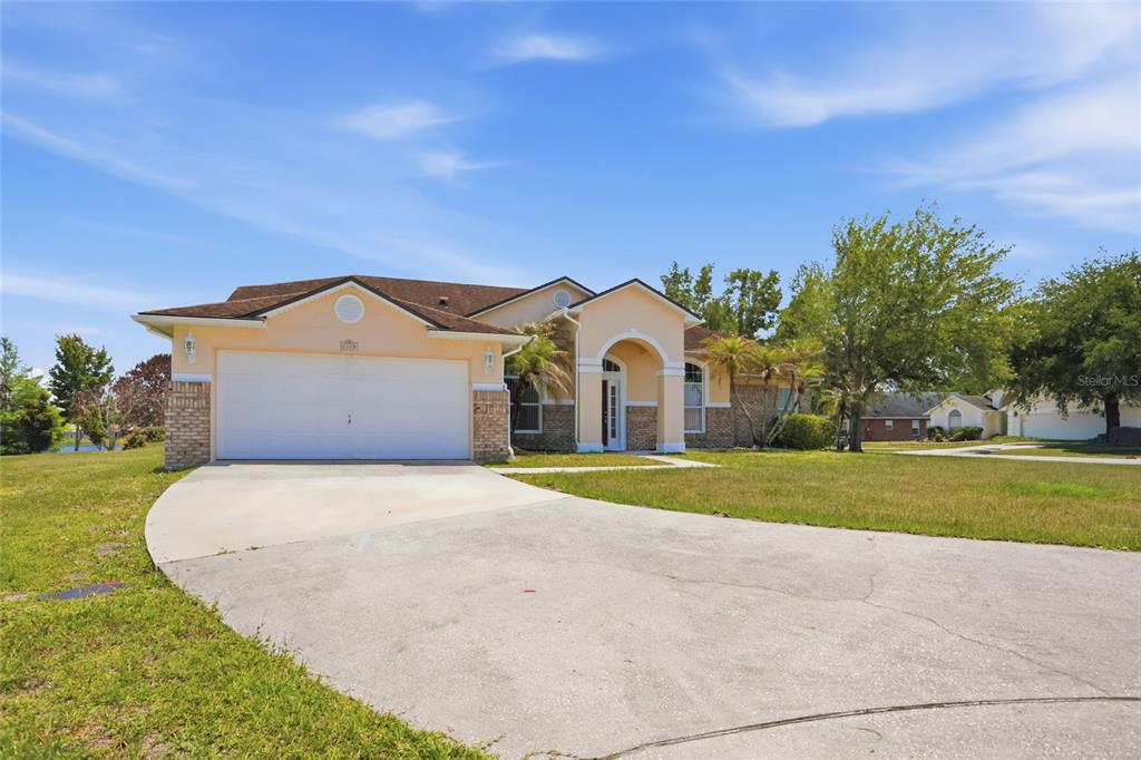 A single-story house with a two-car garage, peach-colored stucco exterior, and a concrete driveway — 2415 TIMOTHY LANE, KISSIMMEE, FL
