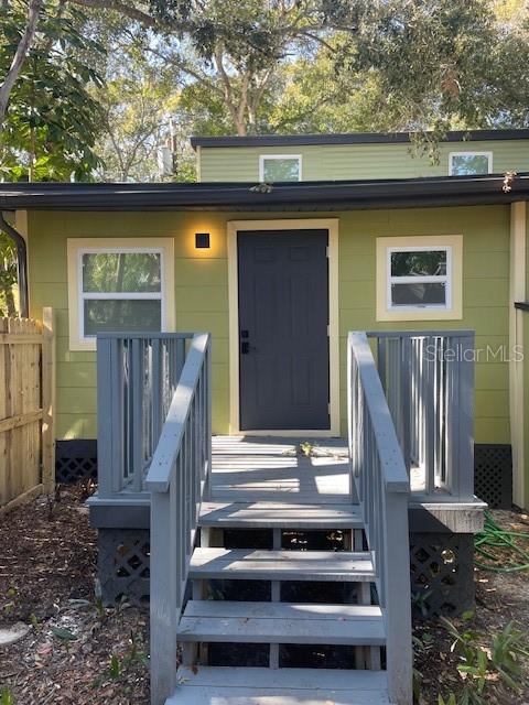 A small green house with a dark front door and a wooden porch with stairs — 1157 HIGHLAND COURT N, ST PETERSBURG, FL