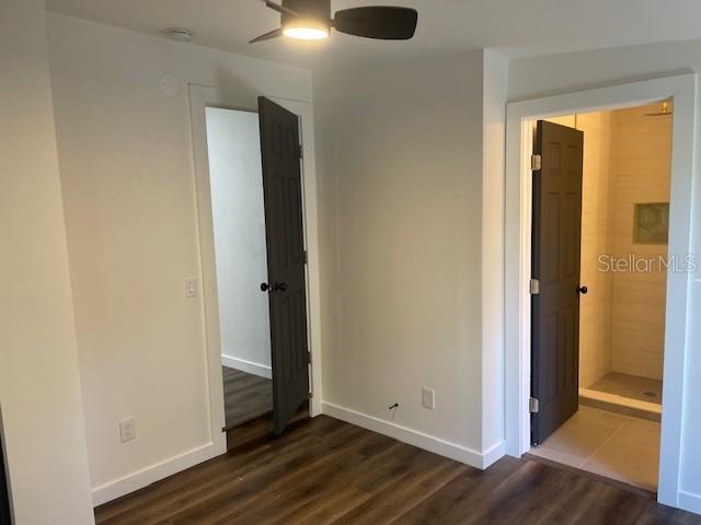 A room with wood-look flooring, two dark doors, and a ceiling fan — 1157 HIGHLAND COURT N, ST PETERSBURG, FL