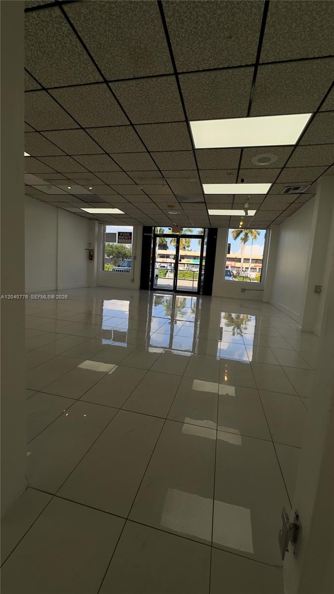An empty commercial space features white tiled floors, a drop ceiling, and large glass windows — 3960 W 16th Ave # 204, Hialeah FL 33012, HIALEAH, FL