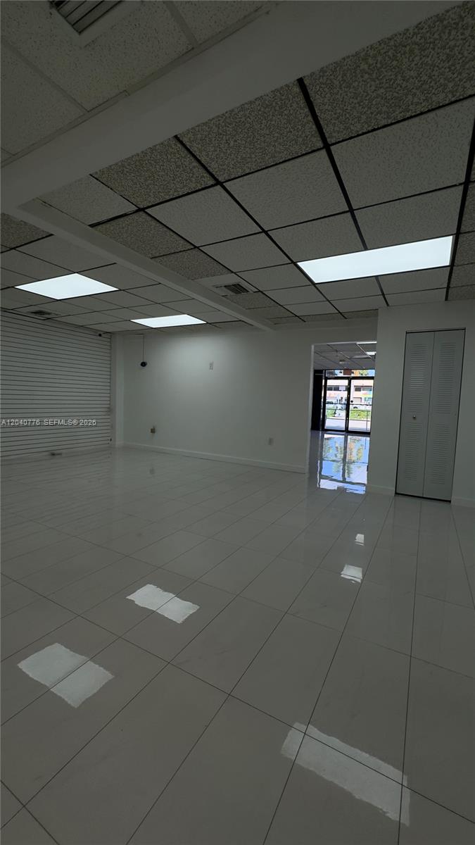 An empty commercial space features white tiled floors, a drop ceiling, and a glass entrance — 3960 W 16th Ave # 204, Hialeah FL 33012, HIALEAH, FL