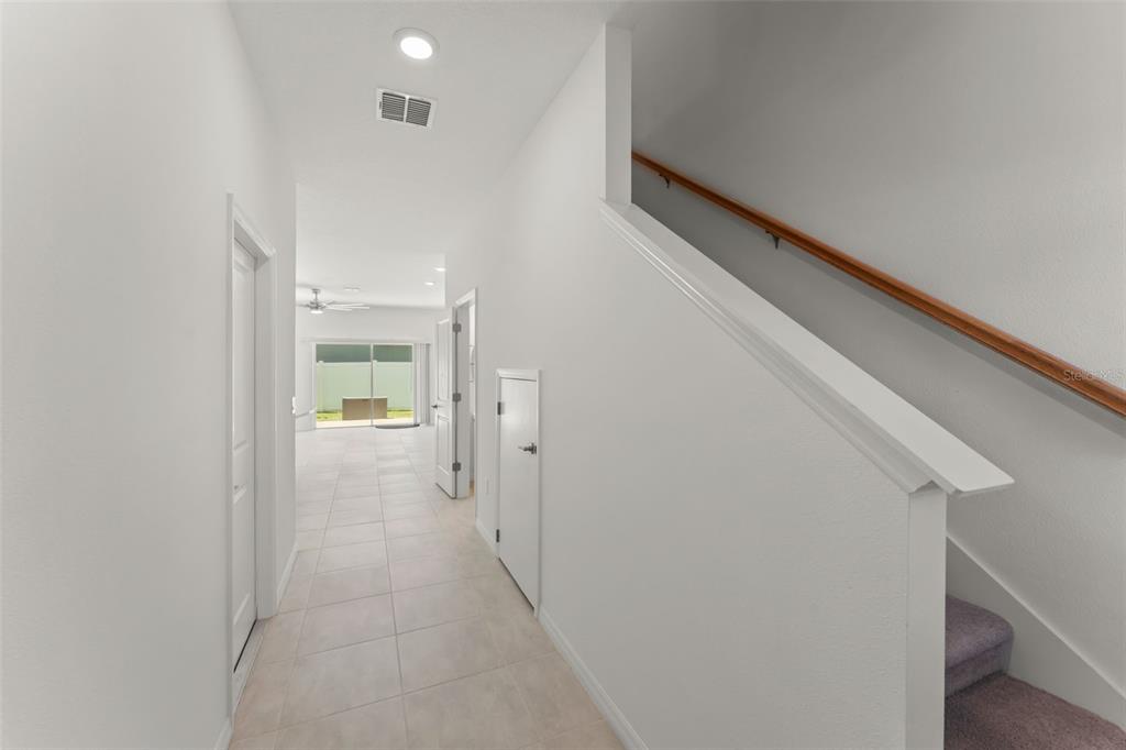 A tiled hallway leads to a living area with a staircase on the right — 3556 LANDING NET DRIVE, KISSIMMEE, FL