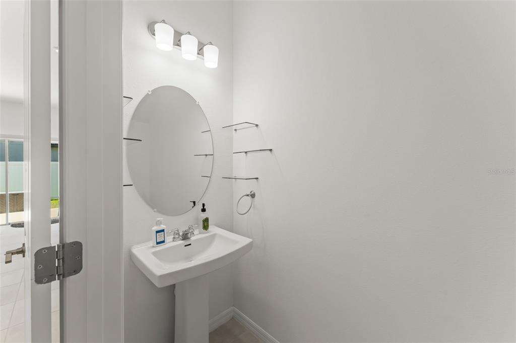 A powder room features a pedestal sink, an oval mirror, and three wall-mounted glass shelves — 3556 LANDING NET DRIVE, KISSIMMEE, FL