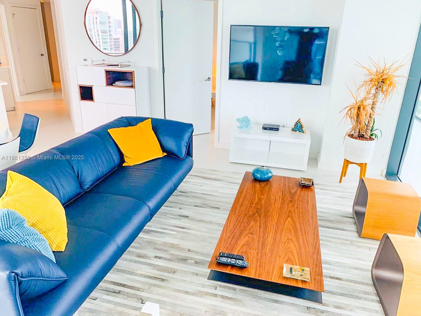 A living room features a blue leather sofa, a wooden coffee table, and a television — 501 NE 31st St # 3906, Miami FL 33137, MIAMI, FL