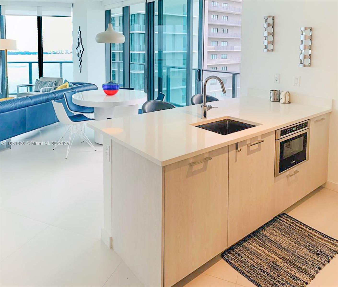 A kitchen island with a sink and built-in oven sits before a dining area — 501 NE 31st St # 3906, Miami FL 33137, MIAMI, FL