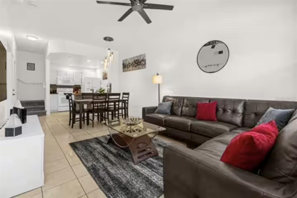 A living room with a dark leather sectional, glass coffee table, and adjacent dining area — 4015 VENETIAN BAY DRIVE UNIT 104, KISSIMMEE, FL