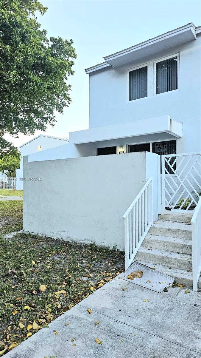 A two-story white townhouse exterior features a concrete staircase leading to a gated entrance — 535 NW 19th St # 369, Miami FL 33136, MIAMI, FL