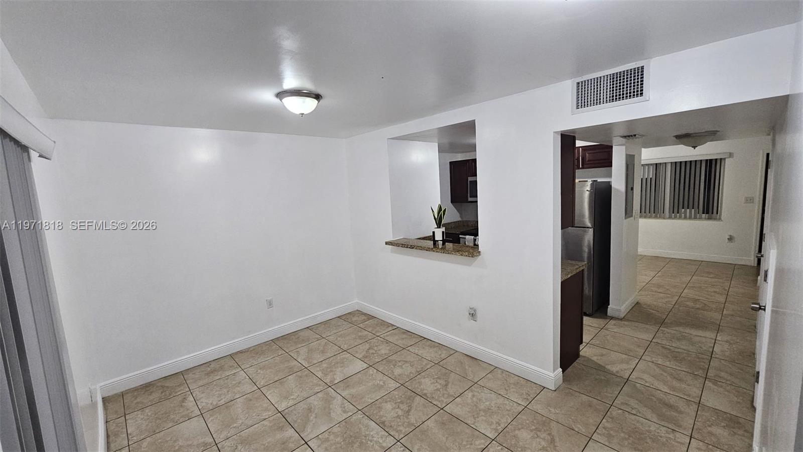A dining area with tile flooring features a pass-through window looking into the kitchen — 535 NW 19th St # 369, Miami FL 33136, MIAMI, FL