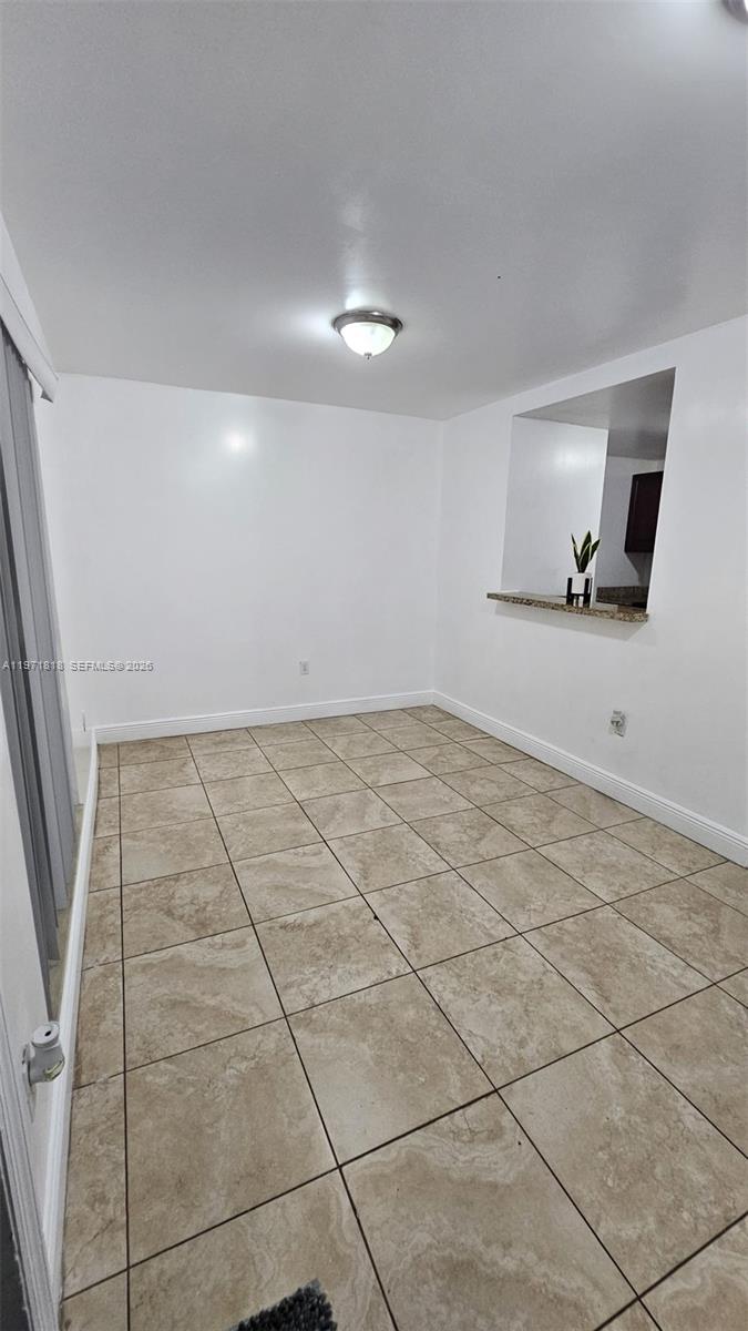 An empty dining area features beige tile flooring, white walls, and a kitchen pass-through window — 535 NW 19th St # 369, Miami FL 33136, MIAMI, FL