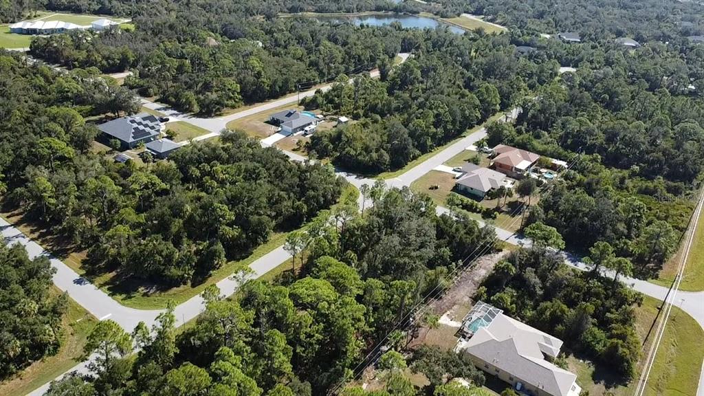 An aerial view shows several houses nestled within a wooded residential neighborhood with paved roads — 1263 BOWMAN TERRACE, PORT CHARLOTTE, FL