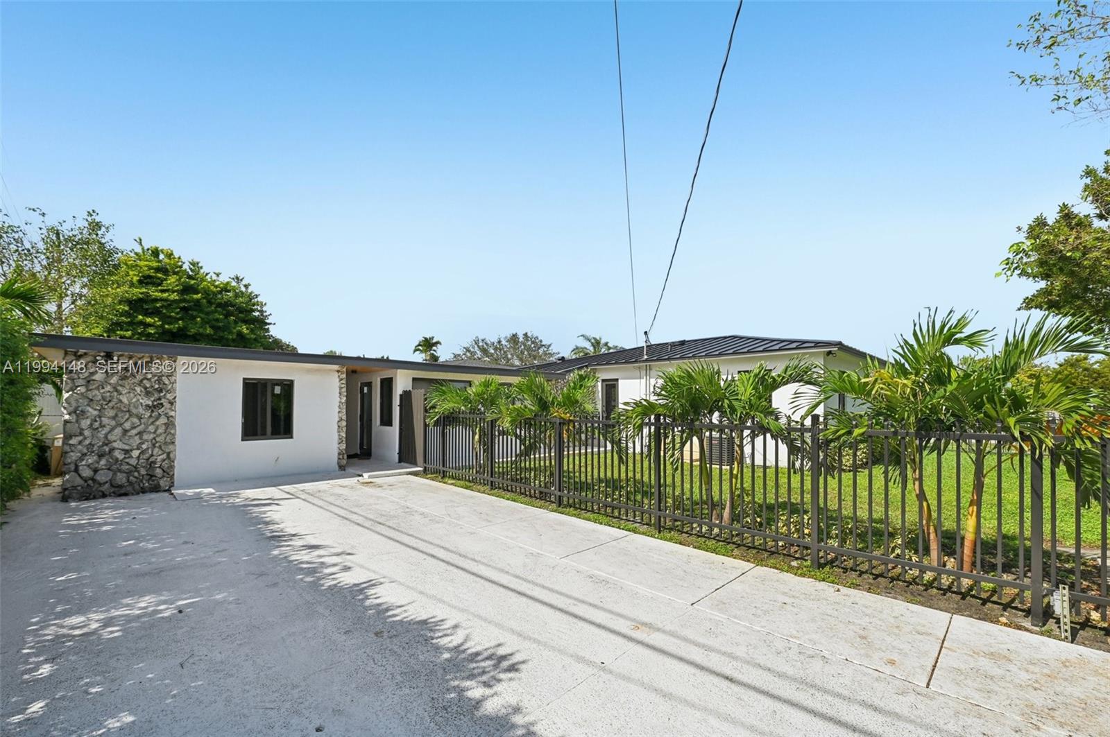 A white house with a stone facade and a metal roof sits behind a fence — 5152 SW 6th St, Miami FL 33134, MIAMI, FL