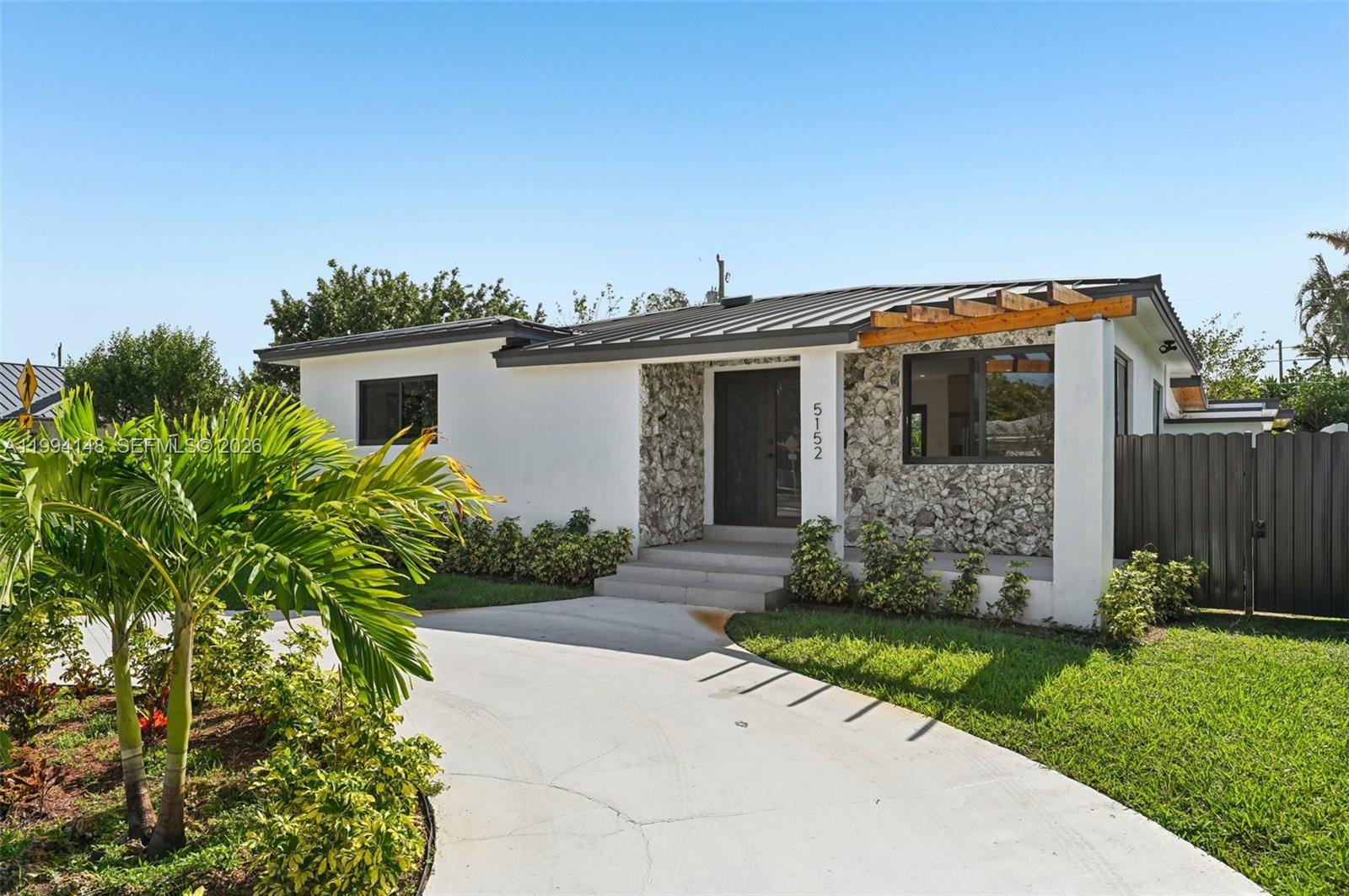 A single-story house features a white stucco exterior, stone facade, and a metal roof — 5152 SW 6th St, Miami FL 33134, MIAMI, FL