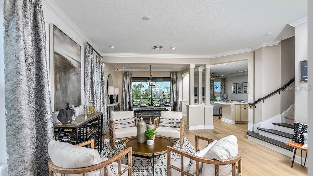 A living room with light wood floors, four armchairs, a coffee table, and a staircase — 5788 PORTICO PLACE, KISSIMMEE, FL