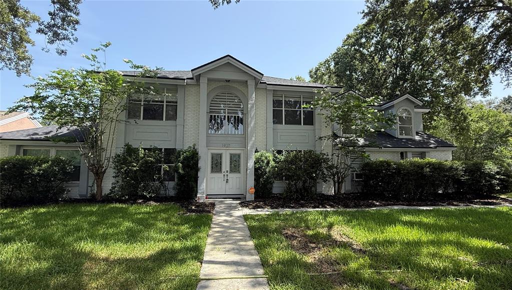A two-story house with a white brick facade, a central arched window, and double front doors — 1927 PALM VIEW DRIVE, APOPKA, FL