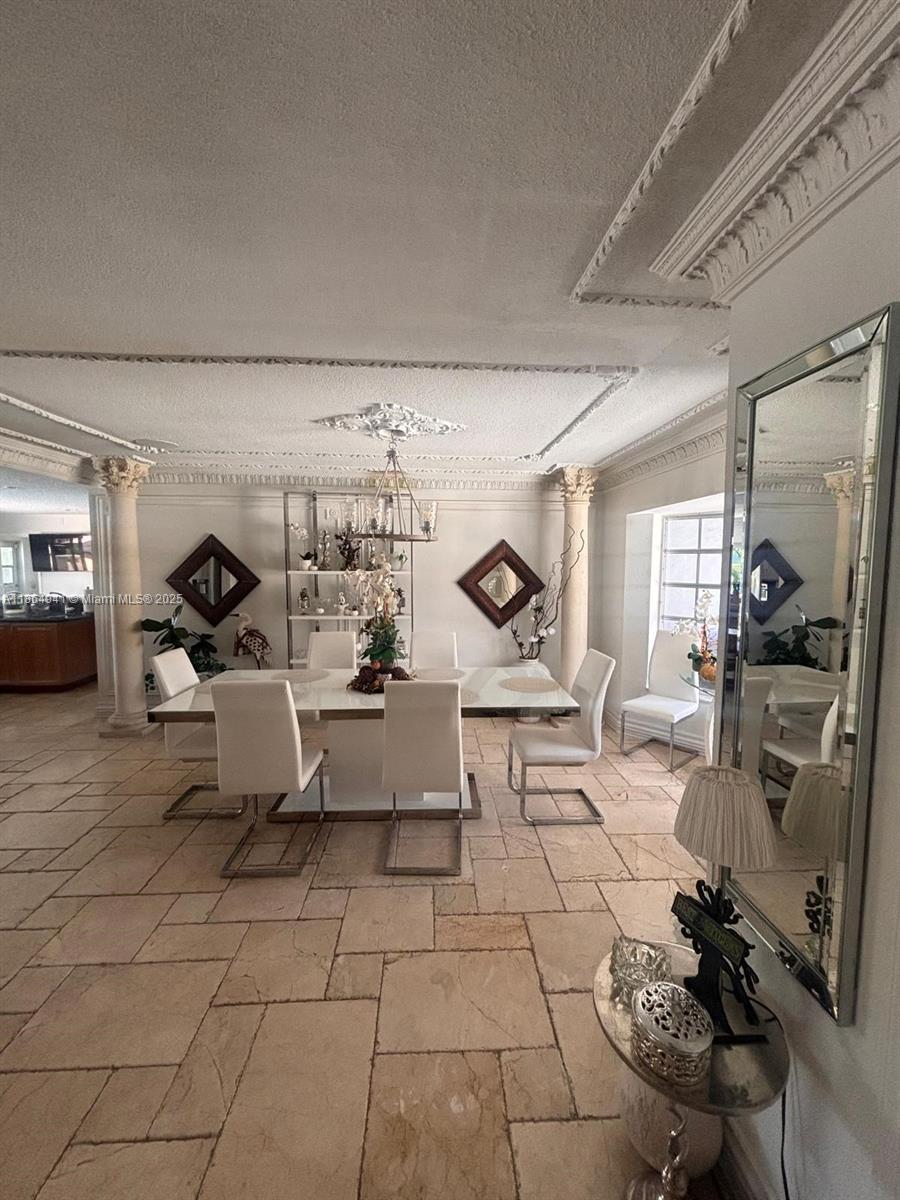 A dining room features a white table, modern chairs, stone flooring, and decorative ceiling molding — 4220 NE 27th Ave, Lighthouse Point FL 33064, LIGHTHOUSE POINT, FL