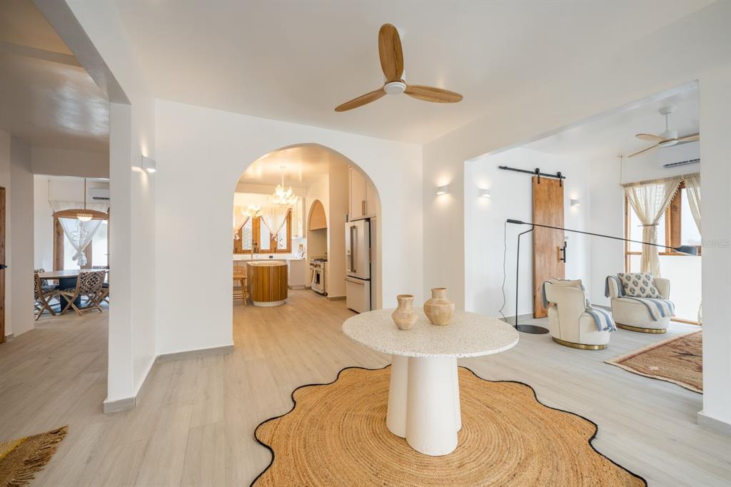 A bright, open-concept living space features a central round table, arched entryway, and wood flooring — 1507 MIRSONIA, SAN JUAN, PR