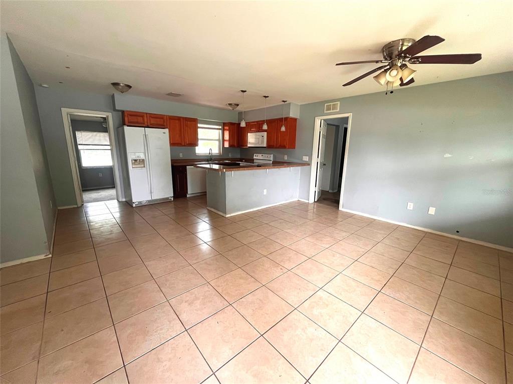 A kitchen with wood cabinets and a breakfast bar opens into a tiled living area — 731 LAKESIDE DRIVE, LARGO, FL