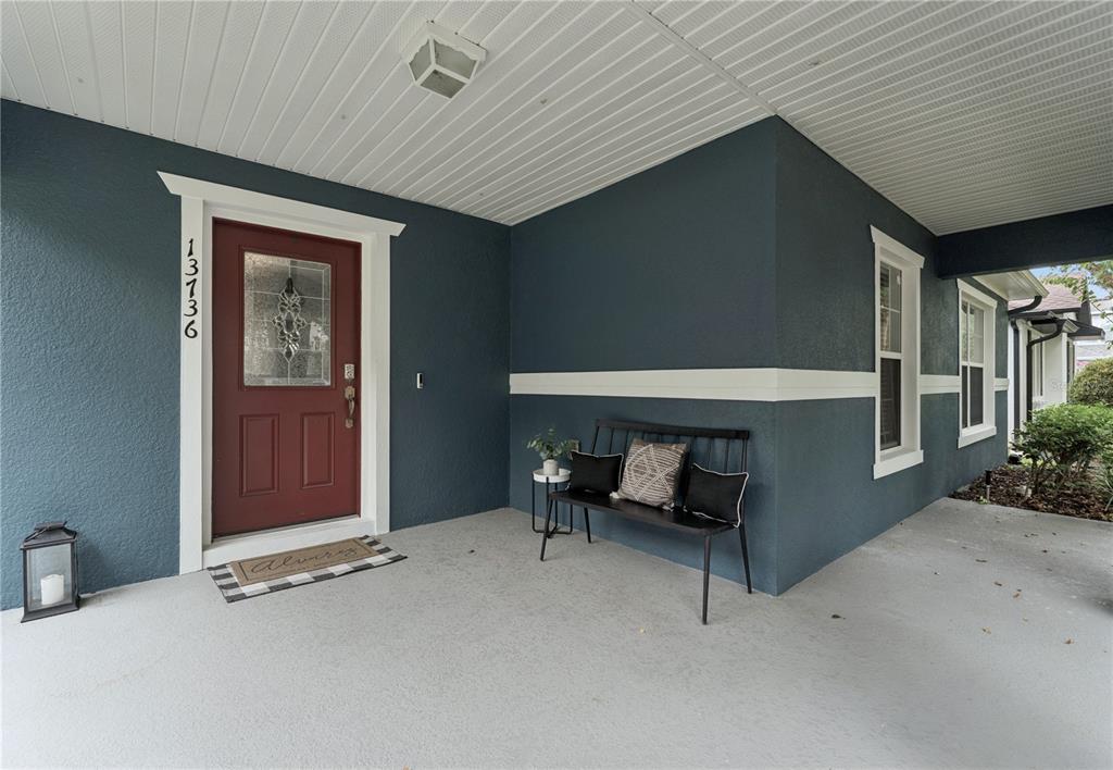 A covered front porch features a red door, a black bench, and blue exterior walls — 13736 PHOENIX DRIVE, ORLANDO, FL