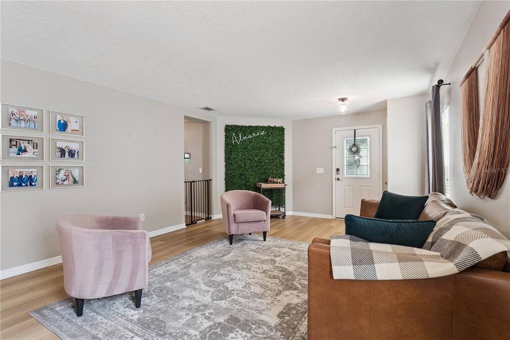 A living room features a sectional sofa, a wall-mounted television, and wood-slat accent wall — 13736 PHOENIX DRIVE, ORLANDO, FL