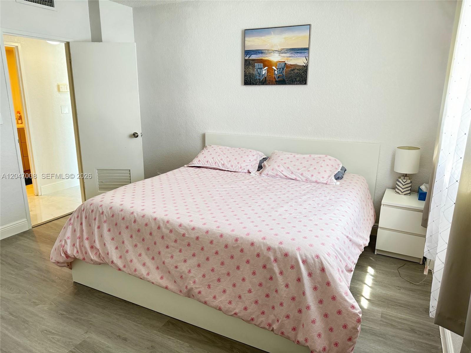 A bedroom features a bed with pink patterned bedding, a white headboard, and a nightstand — 3901 S Ocean Dr # 14Z, Hollywood FL 33019, HOLLYWOOD, FL