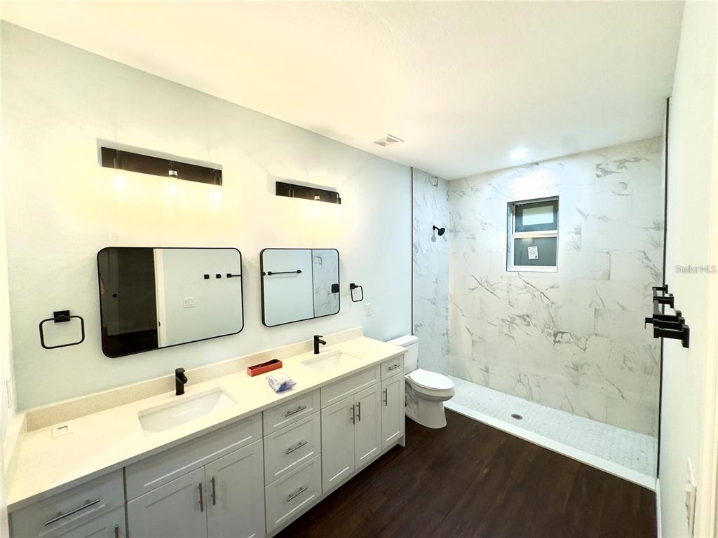 A modern bathroom features a double vanity, a walk-in shower, and marble-look wall tiles — 8169 OLSEN STREET, PORT CHARLOTTE, FL