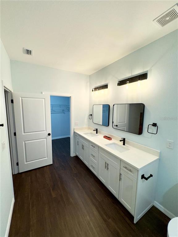 A bathroom features a double vanity with white cabinets, black hardware, and two rectangular mirrors — 8169 OLSEN STREET, PORT CHARLOTTE, FL