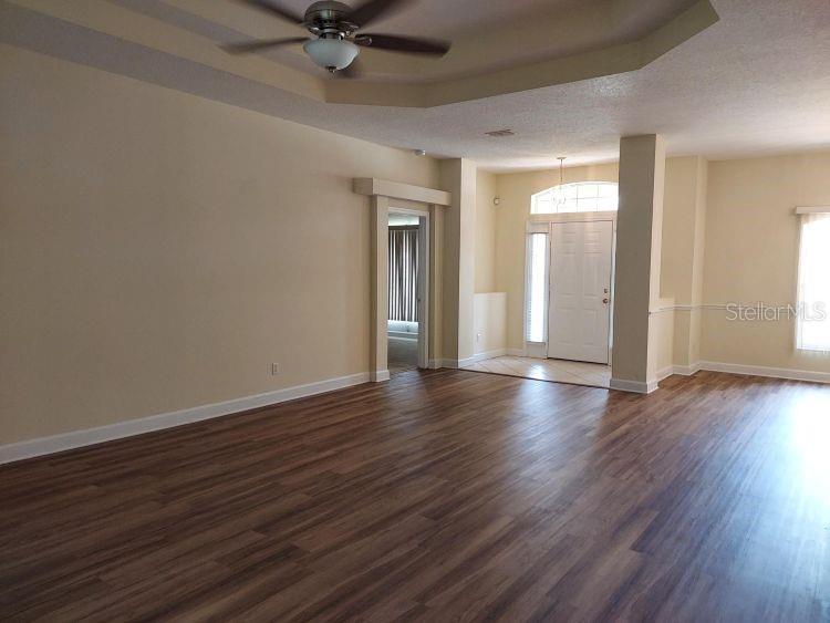 A spacious living area features wood-look flooring, a tray ceiling with a fan, and an entryway — 3 WAINMONT PLACE, PALM COAST, FL