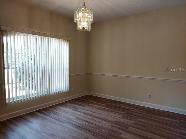 An empty room features wood-look flooring, beige walls with chair rail molding, and vertical blinds — 3 WAINMONT PLACE, PALM COAST, FL