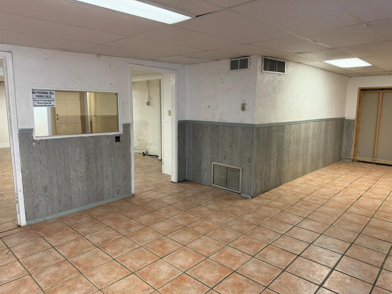 An interior view of a room with tiled floors, wood-paneled wainscoting, and a drop ceiling — 8280 S Us Hwy 17 92, FL 32730, FL
