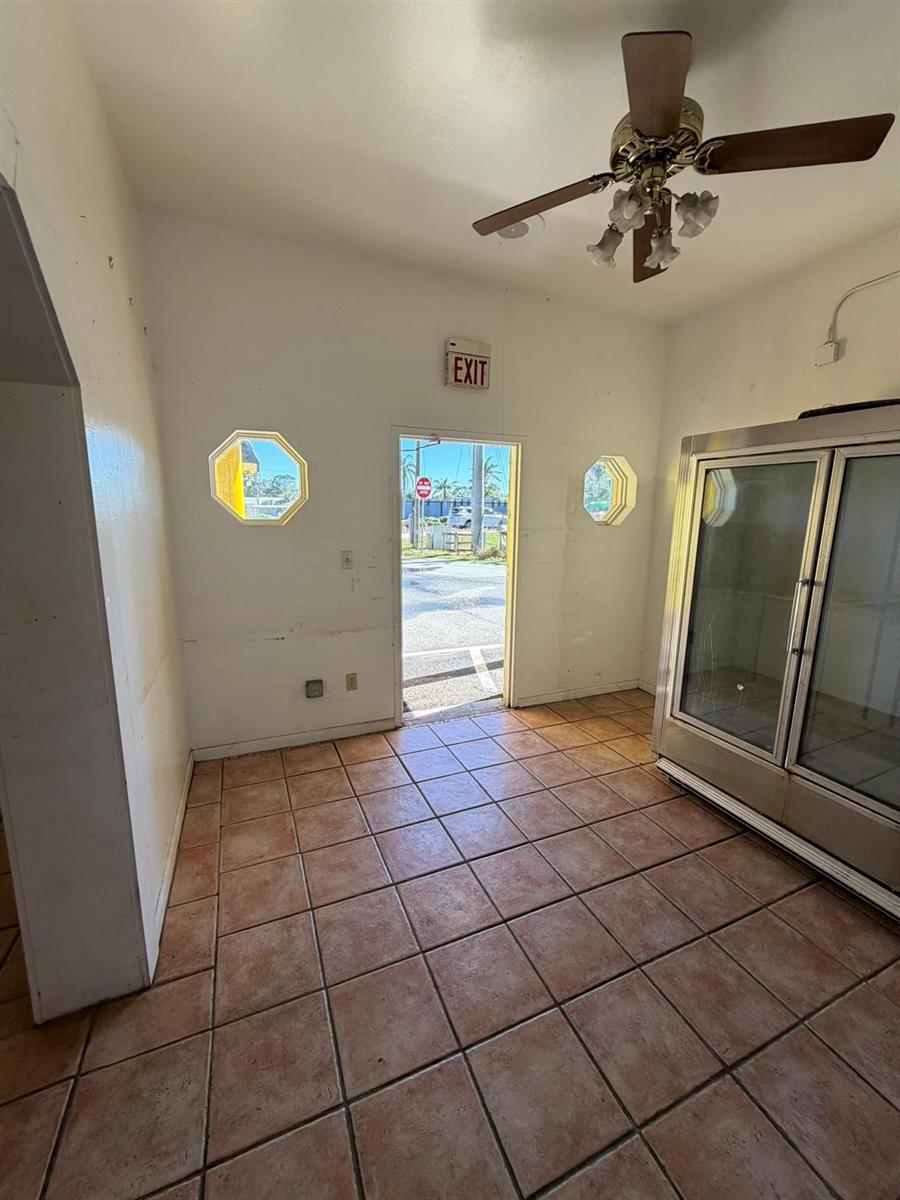 A room with tiled floors, a ceiling fan, an exit door, and a glass-door refrigerator — 8280 S Us Hwy 17 92, FL 32730, FL