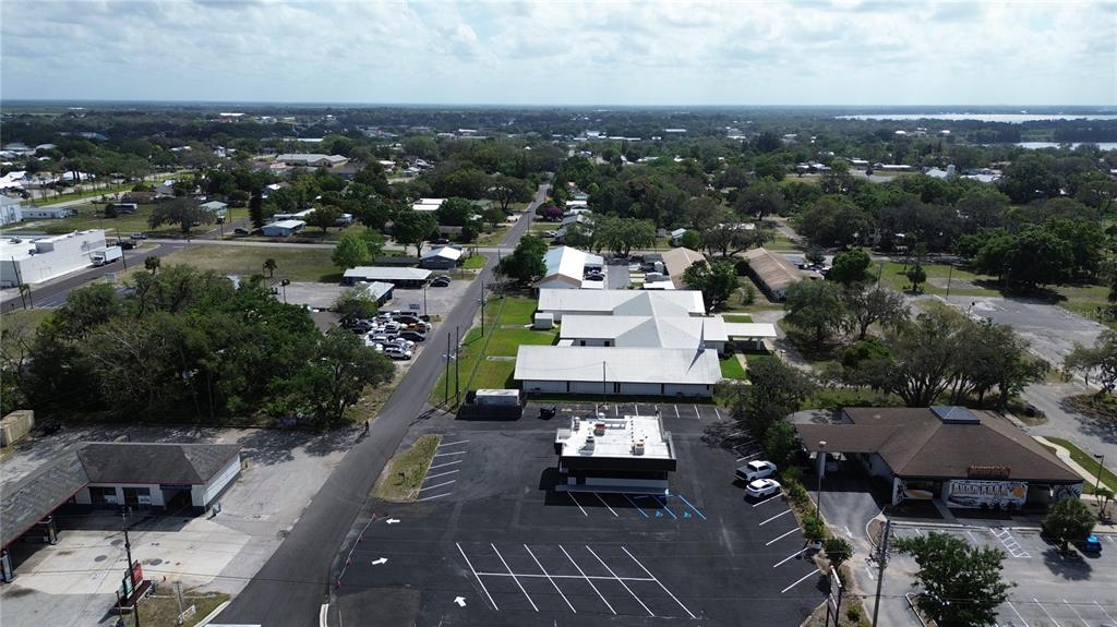 An aerial view shows a commercial parking lot, surrounding buildings, and nearby residential areas — 201 US HIGHWAY 27 S, AVON PARK, FL