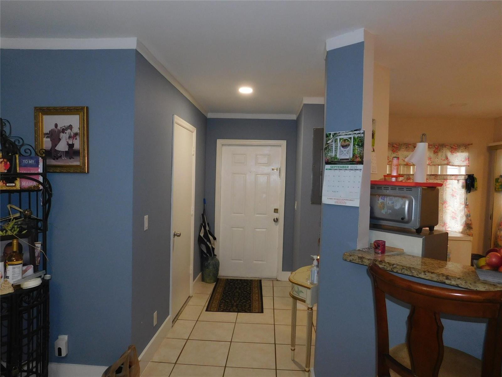 A tiled entryway leads to a white front door with blue walls and a kitchen — 1106 SW 44th Way, Deerfield Beach FL 33442, DEERFIELD BEACH, FL