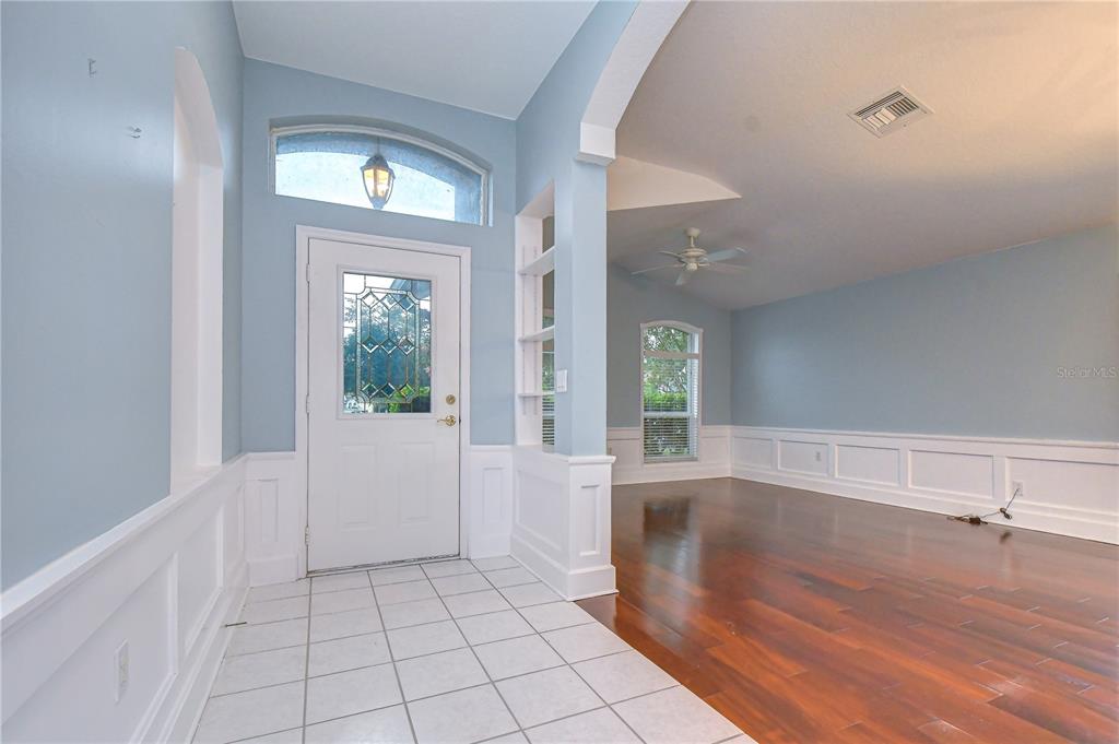 An entryway with white tile flooring leads into a living area with hardwood floors — 19851 ELLENDALE DRIVE, LAND O LAKES, FL