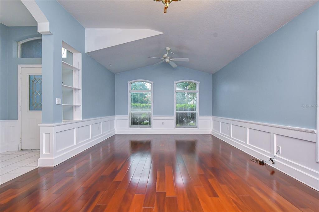 An empty room with blue walls, white wainscoting, hardwood floors, and two tall windows — 19851 ELLENDALE DRIVE, LAND O LAKES, FL