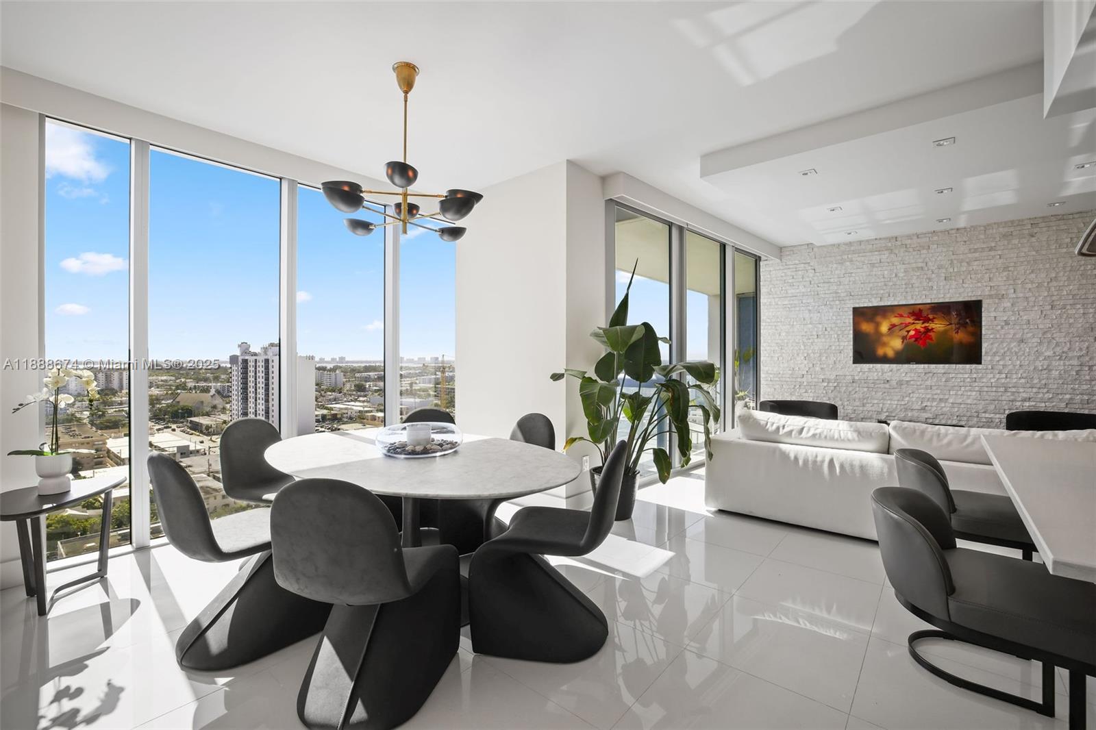 A modern dining area features a round marble table, sculptural chairs, and floor-to-ceiling windows — 6899 Collins Ave # 1610, Miami Beach FL 33141, MIAMI BEACH, FL