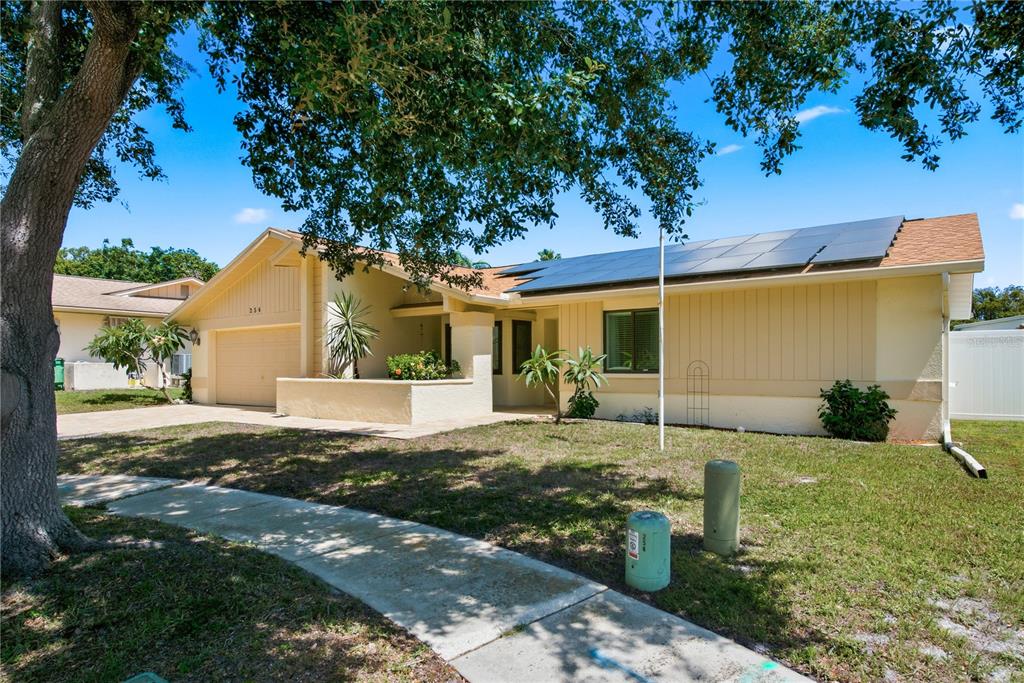 A single-story house with a tan exterior, a garage, and solar panels on the roof — 254 TIMBERVIEW DRIVE, SAFETY HARBOR, FL