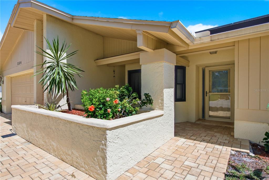 The exterior view shows a beige house with a brick paver walkway and landscaping — 254 TIMBERVIEW DRIVE, SAFETY HARBOR, FL
