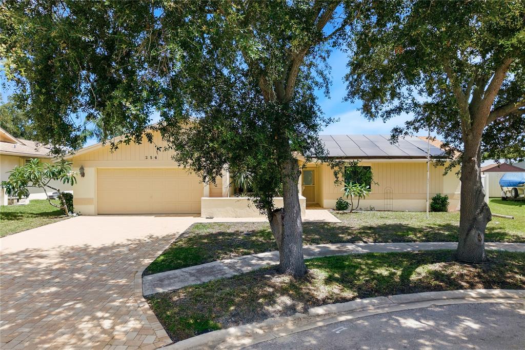 A single-story house with a beige exterior, a two-car garage, and solar panels on the roof — 254 TIMBERVIEW DRIVE, SAFETY HARBOR, FL