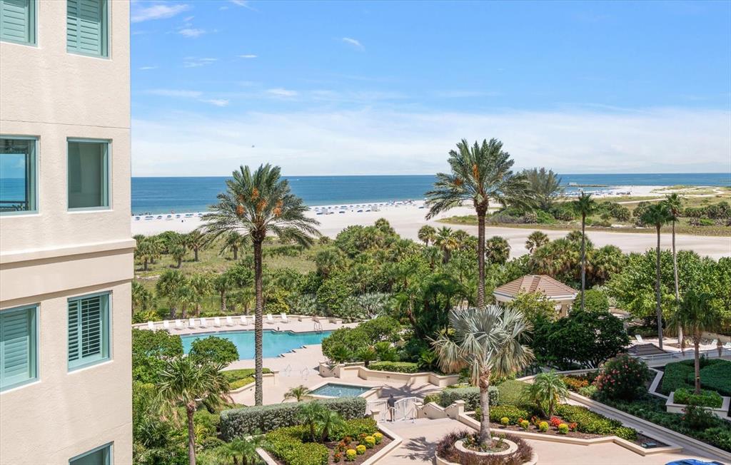 An elevated view of a beach resort pool area with palm trees and the ocean — 1180 GULF BLVD UNIT 504, CLEARWATER BEACH, FL