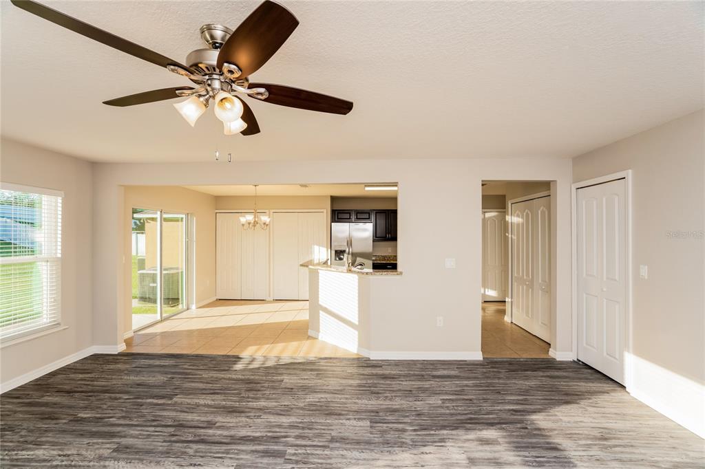 A living room with wood-look flooring opens to a kitchen and dining area with tile — 13307 WATERFORD CASTLE DRIVE, DADE CITY, FL